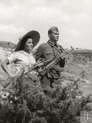 A woman and man holding guns on a hillside